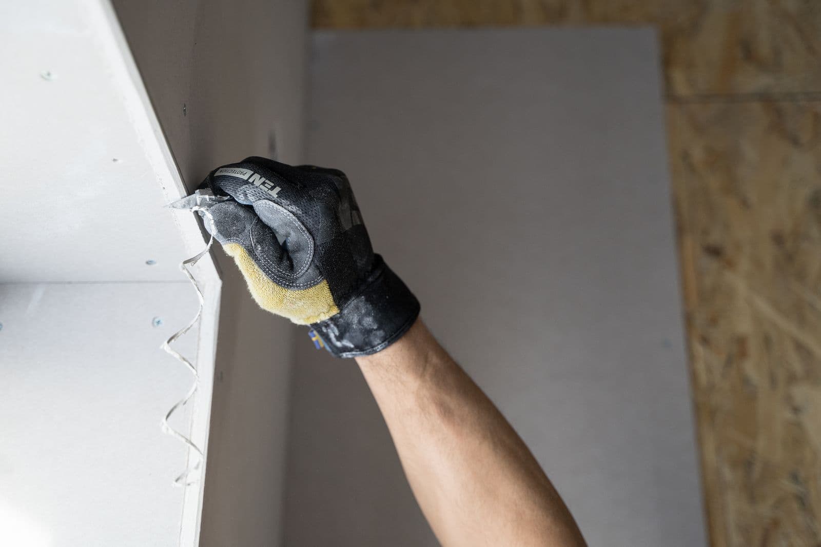 Gloved hand finishing new drywall during water damage repairs
